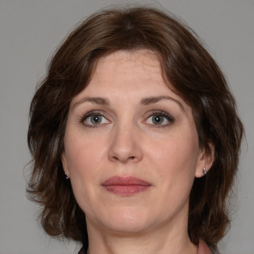 Joyful white adult female with medium  brown hair and green eyes