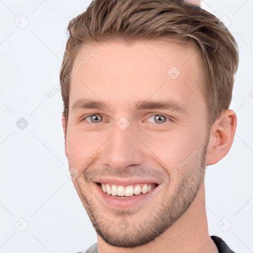 Joyful white young-adult male with short  brown hair and grey eyes