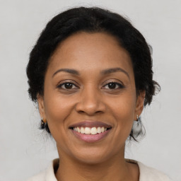 Joyful black adult female with medium  brown hair and brown eyes