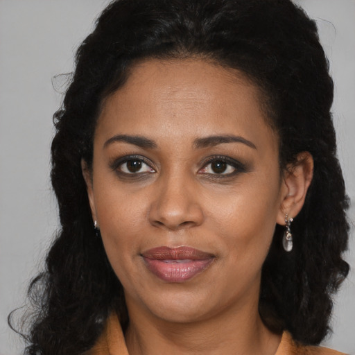 Joyful black young-adult female with long  brown hair and brown eyes