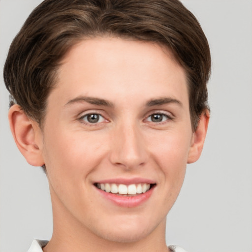 Joyful white young-adult female with short  brown hair and grey eyes