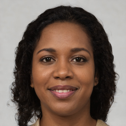 Joyful black young-adult female with long  brown hair and brown eyes