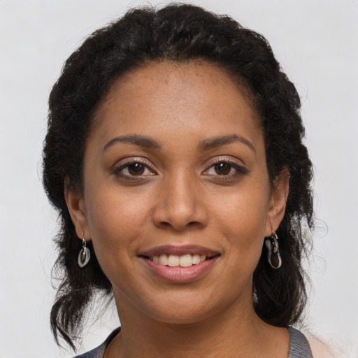 Joyful black young-adult female with long  brown hair and brown eyes