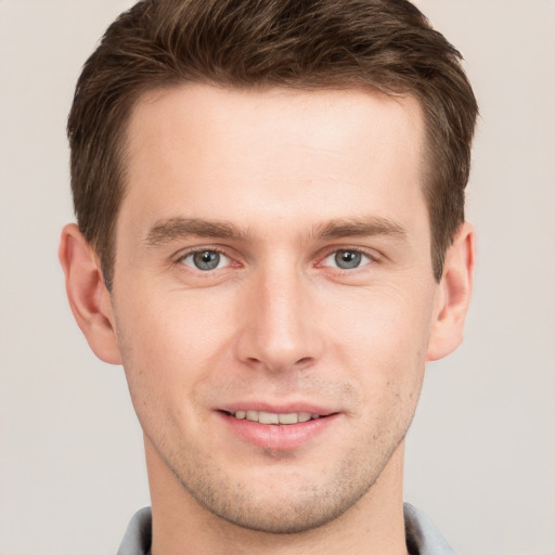 Joyful white young-adult male with short  brown hair and grey eyes