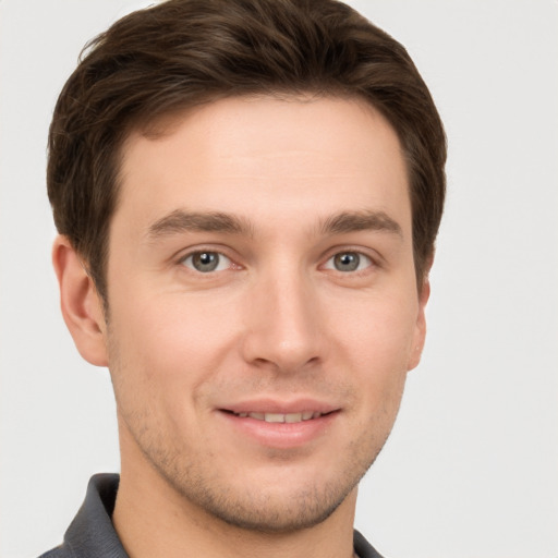 Joyful white young-adult male with short  brown hair and grey eyes