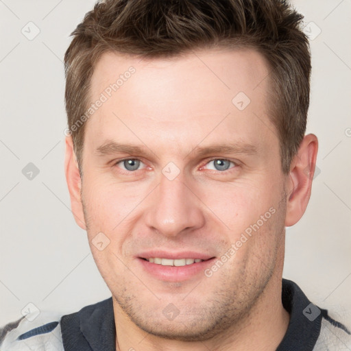 Joyful white young-adult male with short  brown hair and grey eyes