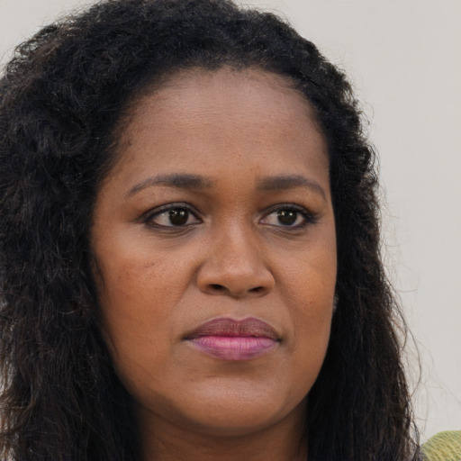 Joyful black young-adult female with long  brown hair and brown eyes