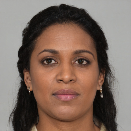 Joyful black young-adult female with long  brown hair and brown eyes