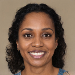 Joyful black young-adult female with long  brown hair and brown eyes