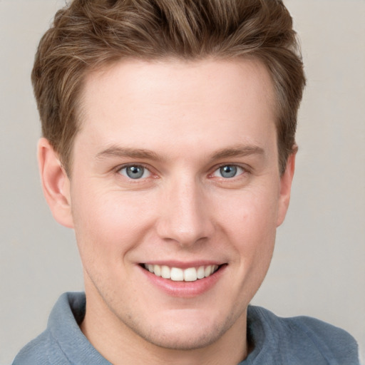 Joyful white young-adult male with short  brown hair and blue eyes