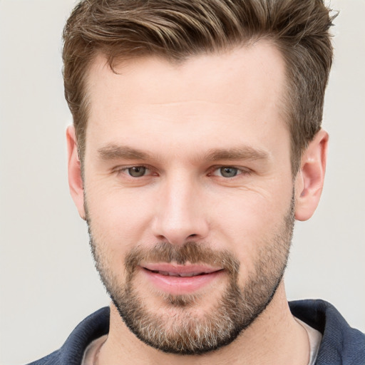 Joyful white young-adult male with short  brown hair and grey eyes