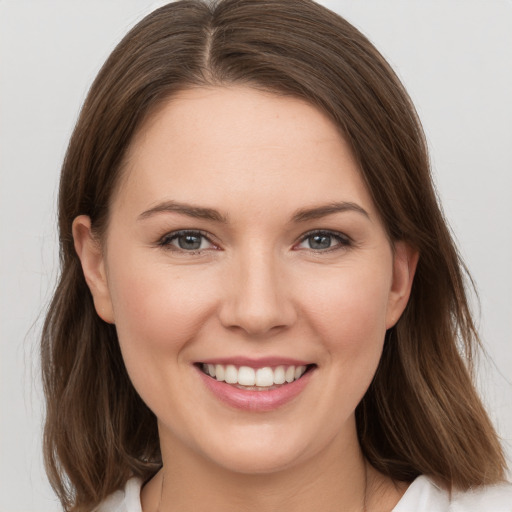 Joyful white young-adult female with medium  brown hair and grey eyes