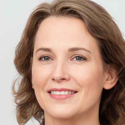 Joyful white adult female with long  brown hair and grey eyes