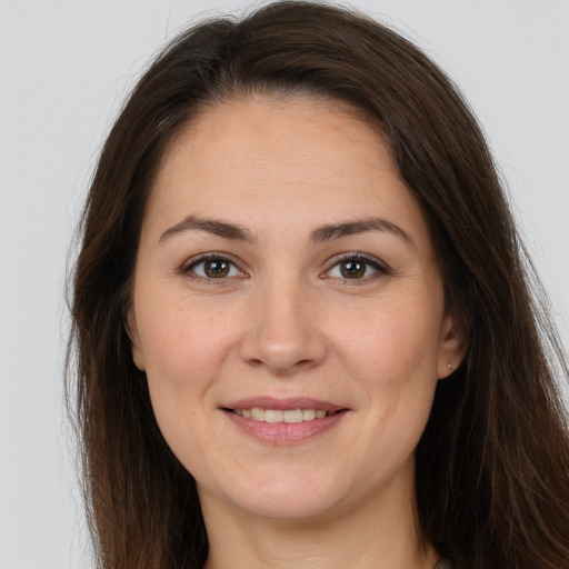 Joyful white young-adult female with long  brown hair and brown eyes