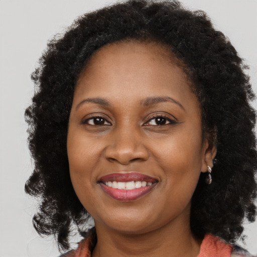 Joyful black adult female with long  brown hair and brown eyes