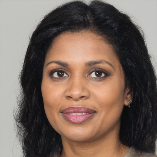 Joyful black young-adult female with long  brown hair and brown eyes