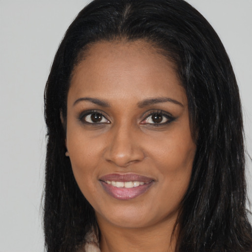 Joyful black young-adult female with long  brown hair and brown eyes