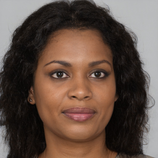 Joyful black young-adult female with long  brown hair and brown eyes