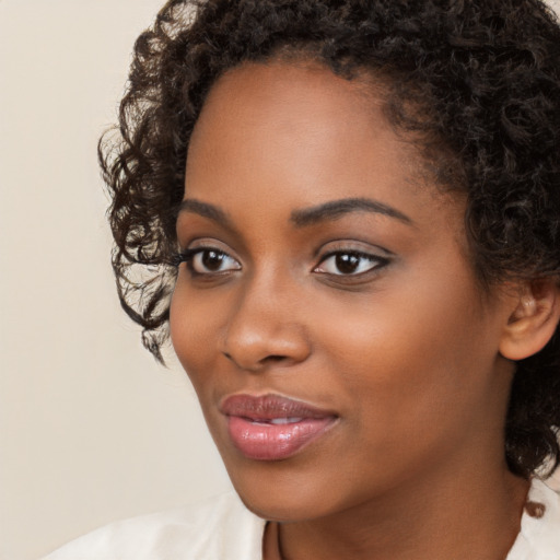 Joyful black young-adult female with long  brown hair and brown eyes