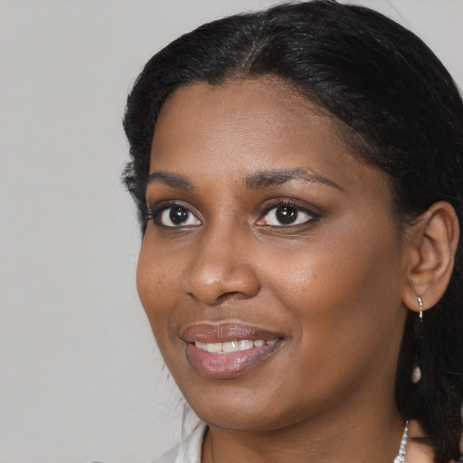 Joyful black young-adult female with long  black hair and brown eyes