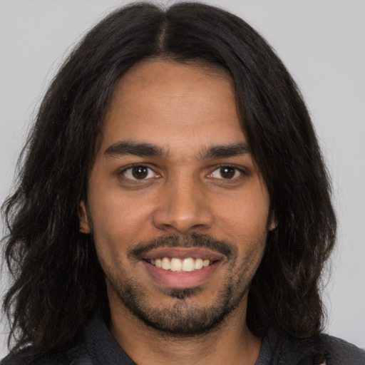 Joyful latino young-adult male with long  brown hair and brown eyes