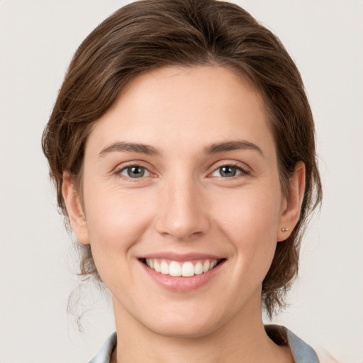 Joyful white young-adult female with medium  brown hair and grey eyes