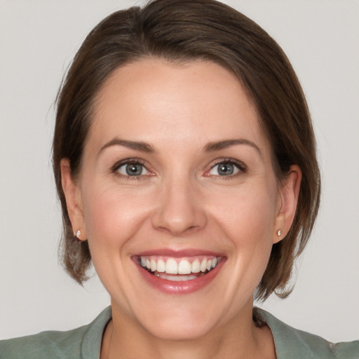 Joyful white young-adult female with medium  brown hair and grey eyes