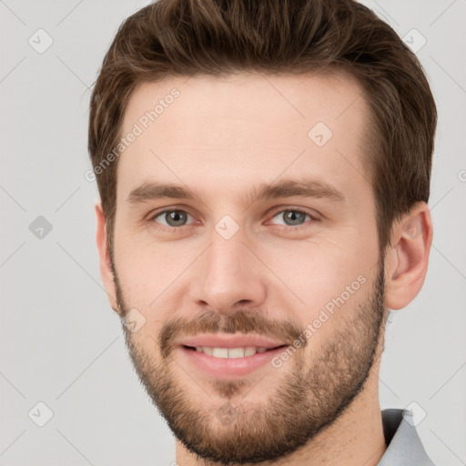 Joyful white young-adult male with short  brown hair and grey eyes