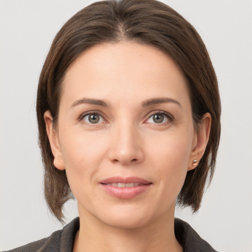 Joyful white young-adult female with medium  brown hair and grey eyes