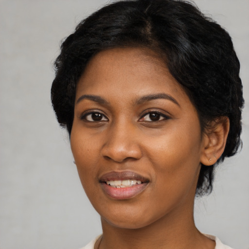 Joyful black young-adult female with short  black hair and brown eyes