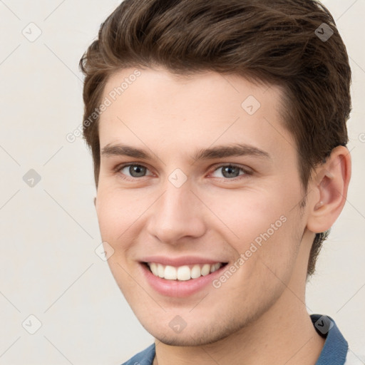 Joyful white young-adult male with short  brown hair and grey eyes