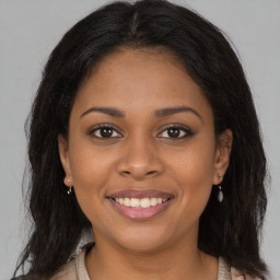 Joyful black young-adult female with long  brown hair and brown eyes