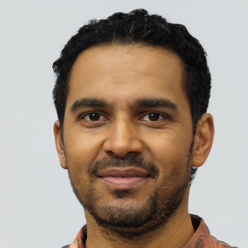 Joyful black young-adult male with short  black hair and brown eyes