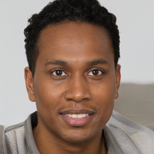 Joyful black young-adult male with short  brown hair and brown eyes