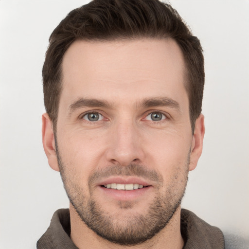 Joyful white young-adult male with short  brown hair and grey eyes