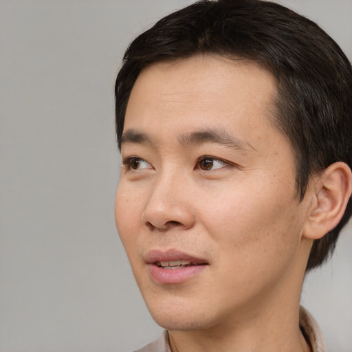 Joyful asian young-adult male with short  brown hair and brown eyes