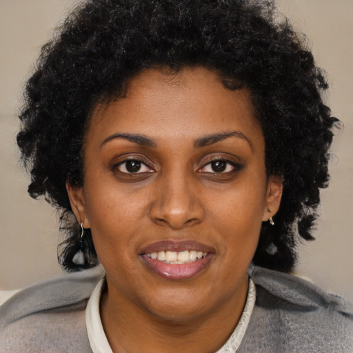 Joyful black young-adult female with short  black hair and brown eyes