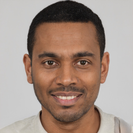Joyful black young-adult male with short  black hair and brown eyes
