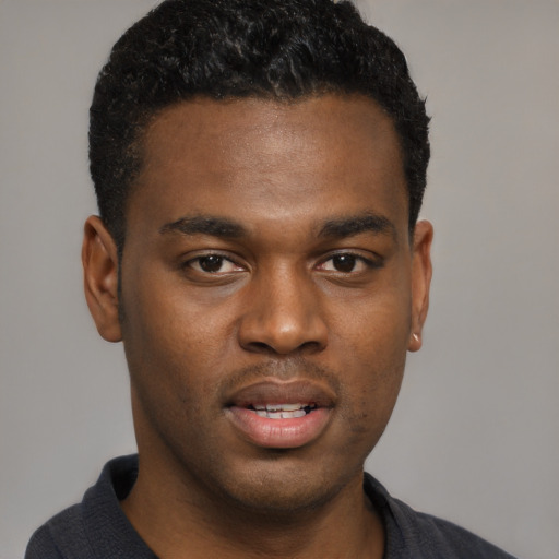 Joyful black young-adult male with short  black hair and brown eyes