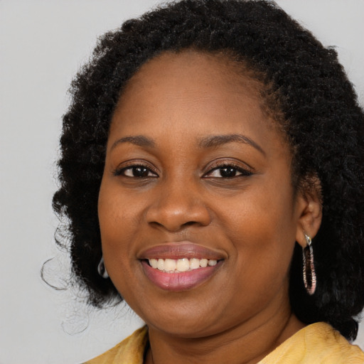 Joyful black young-adult female with long  black hair and brown eyes