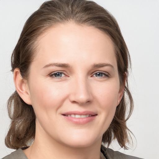 Joyful white young-adult female with medium  brown hair and grey eyes