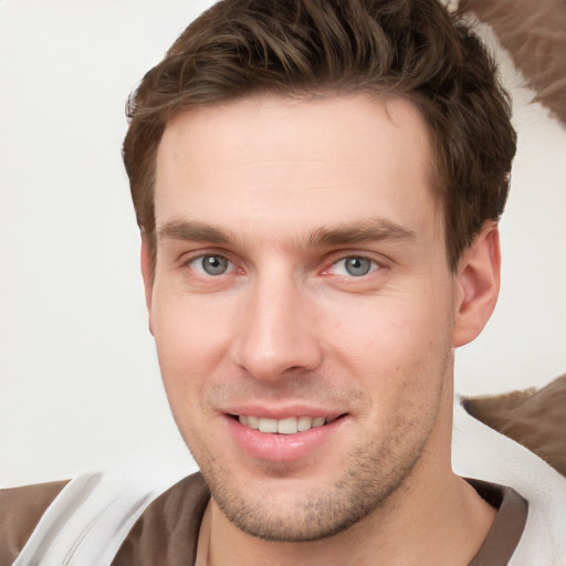 Joyful white young-adult male with short  brown hair and grey eyes