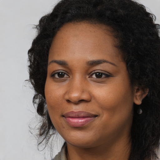 Joyful black young-adult female with long  black hair and brown eyes