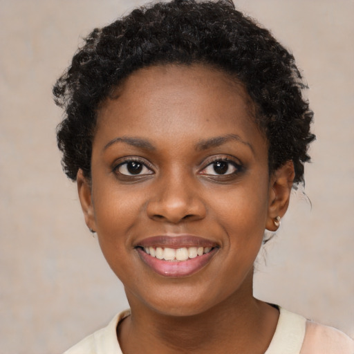 Joyful black young-adult female with short  black hair and brown eyes