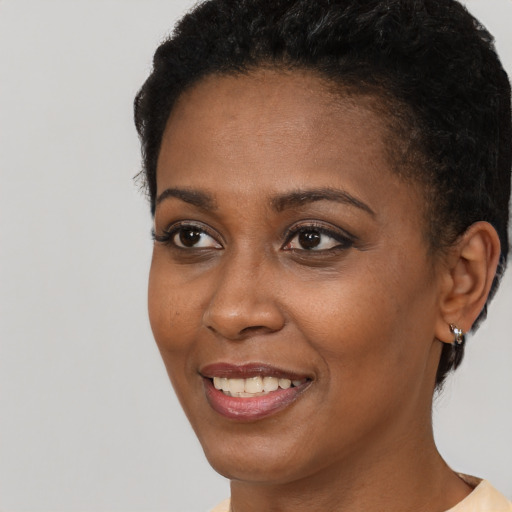 Joyful black young-adult female with short  black hair and brown eyes
