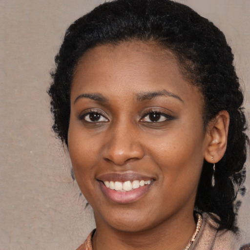 Joyful black young-adult female with long  black hair and brown eyes