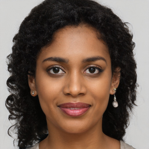 Joyful black young-adult female with long  black hair and brown eyes
