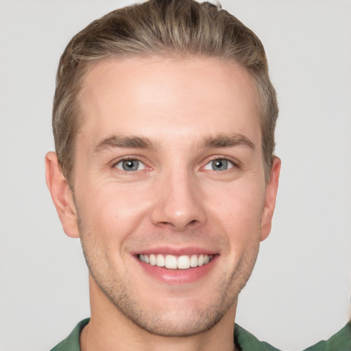 Joyful white young-adult male with short  brown hair and grey eyes