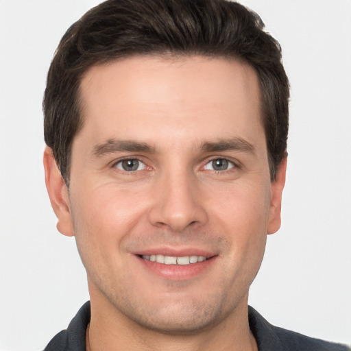 Joyful white young-adult male with short  brown hair and grey eyes