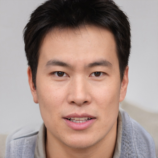 Joyful asian young-adult male with short  brown hair and brown eyes
